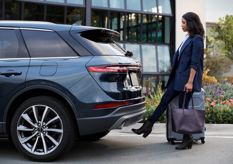 A woman with luggage and a bag opens the available hands-free liftgate by kicking her foot under the bumper | Irwin Lincoln in Freehold NJ