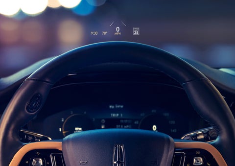 The available head-up display projects data on the windshield above the steering wheel inside a 2022 Lincoln Corsair as the driver navigates the city at night | Irwin Lincoln in Freehold NJ