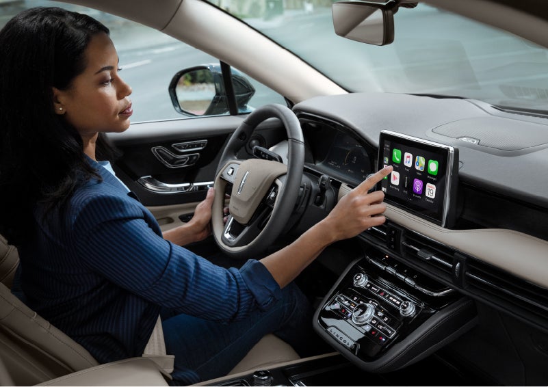 A woman in the driver’s seat of a 2022 Lincoln Corsair is touching the center digital screen to connect to Apple CarPlay<sup>®</sup> | Irwin Lincoln in Freehold NJ