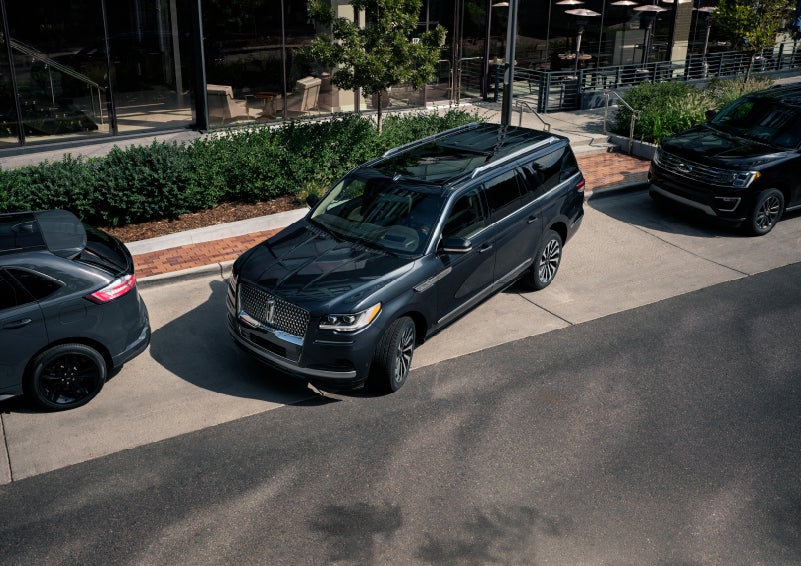 A 2022 Lincoln Navigator SUV is being parallel parked between two vehicles on a downtown street outside of a luxury hotel | Irwin Lincoln in Freehold NJ