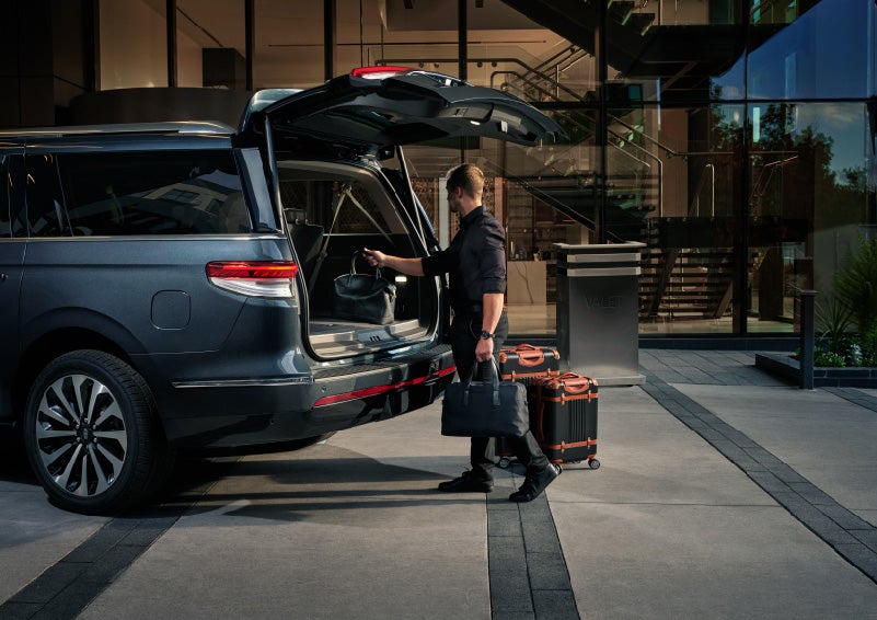 A valet is unloading luggage from the rear cargo area of a 2022 Lincoln Navigator SUV | Irwin Lincoln in Freehold NJ