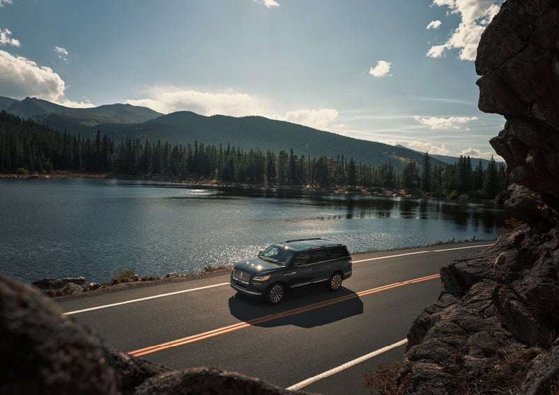 A 2022 Lincoln Navigator SUV is driving along a lake high up in the mountains | Irwin Lincoln in Freehold NJ