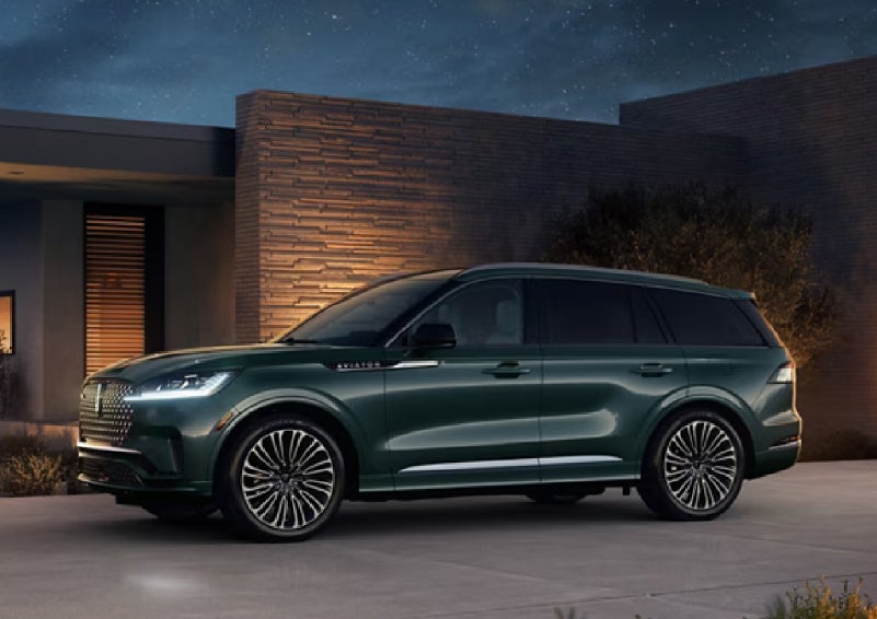 A green 2027 Lincoln Aviator® SUV is parked outside a contemporary home. | Irwin Lincoln in Freehold NJ