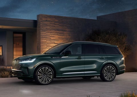 A green 2027 Lincoln Aviator® SUV is parked outside a contemporary home. | Irwin Lincoln in Freehold NJ